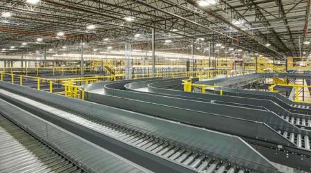 A brand-new room full of industrial racking and a large conveyor system inside the Wilton Industries warehouse.