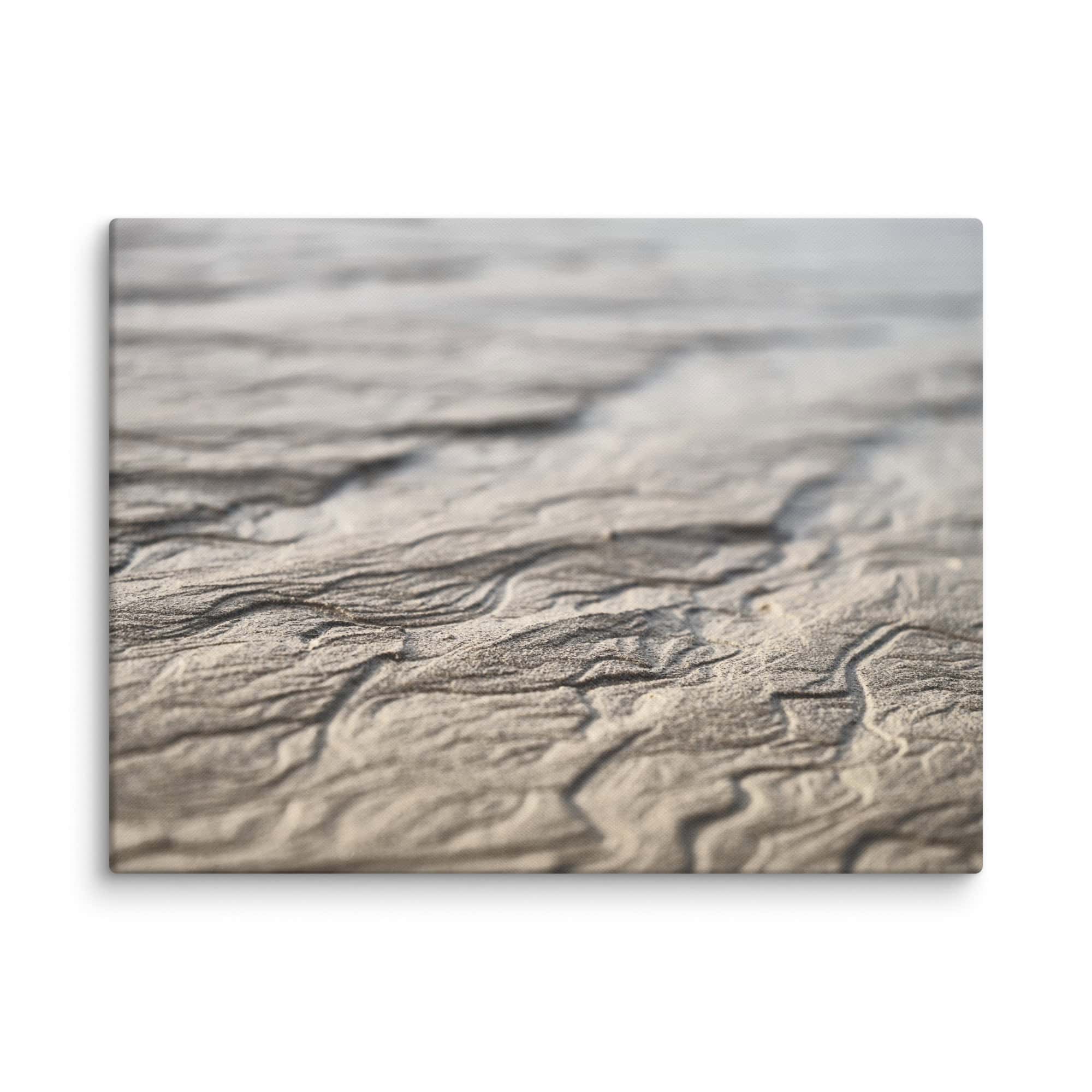 Primer plano de patrones de arena ondulada en una playa en Paisajes Canarios, con iluminación suave y poca profundidad de campo. La textura y las líneas crean una atmósfera tranquila y serena, capturando la belleza natural de la costa como una pieza titulada *Lienzo Surcos Arena Mojada*.