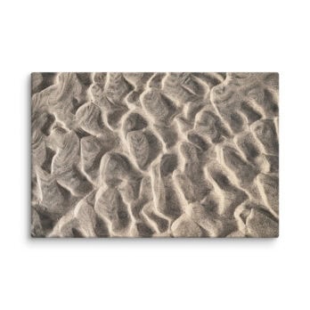 Una vista en primer plano de patrones de arena ondulada en una playa, que recuerdan al "Lienzo surcos del viento sobre arena mojada", muestra las intrincadas texturas onduladas que se forman naturalmente por el movimiento del viento o el agua. Esta impresionante imagen es perfecta para impresiones fotográficas y está disponible en nuestra tienda en línea.