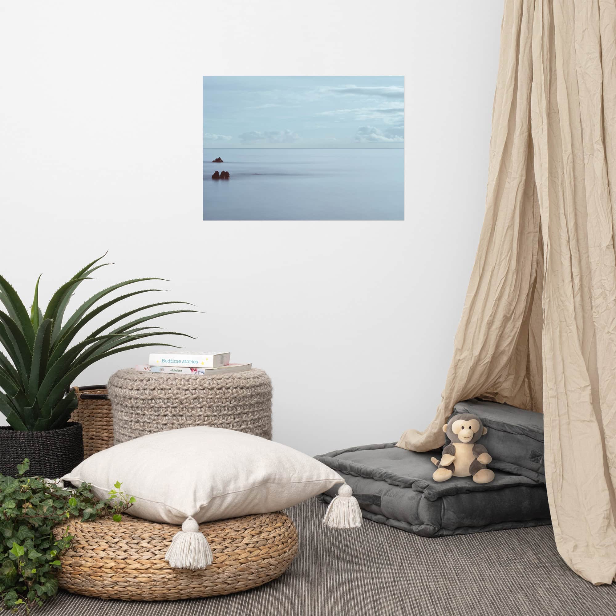 Una acogedora habitación decorada con tonos neutros incluye un puf tejido, una pila de cojines de suelo grises y un dosel drapeado en color beige. Una planta en maceta y un mono de peluche aportan calidez, mientras que el cartel "Mar en calma en Los Cancajos" colgado en la pared completa la decoración.