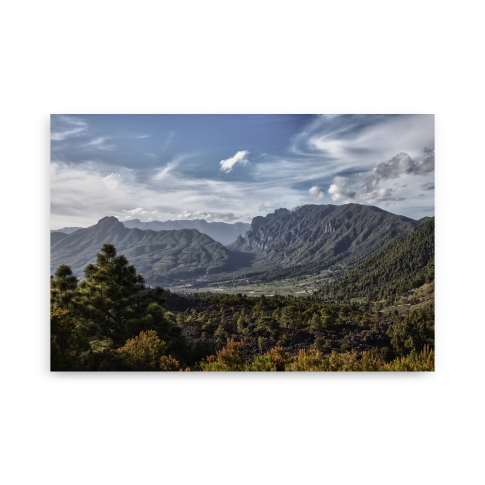 El póster Caldera de Taburiente captura de forma hermosa una vista panorámica de un paisaje montañoso con una vegetación exuberante en primer plano. El cielo parcialmente nublado crea un contraste dramático con las colinas y los valles, ofreciendo una decoración perfecta para cualquier espacio.
