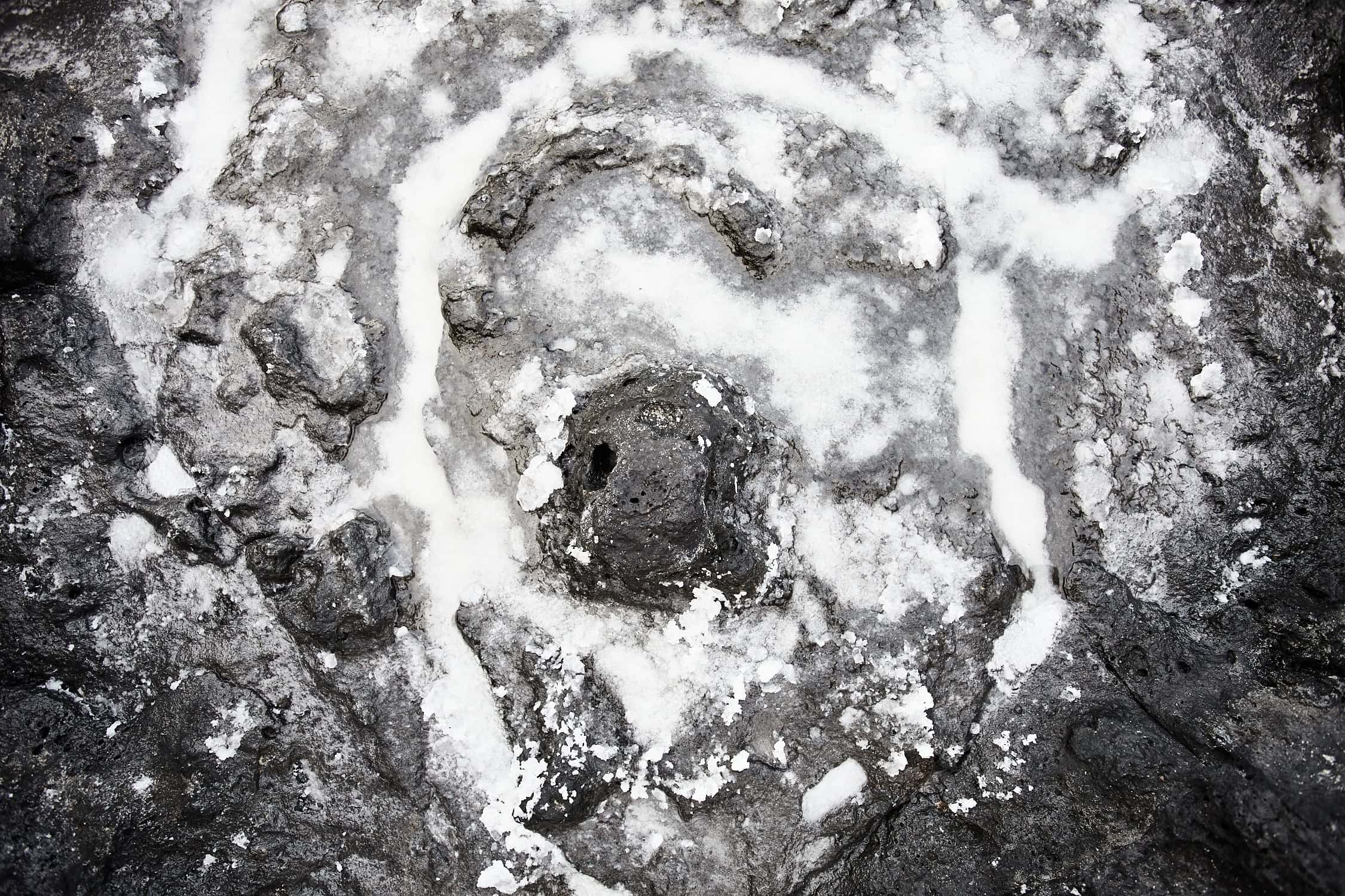 En la oscura y rocosa superficie de La Palma, el "Lienzo roca y sal" presenta una disposición de líneas de sal blanca en espiral alrededor de un agujero central. La textura rugosa realza el Arte Decorativo de la isla, con sal cristalizándose artísticamente en varias áreas, lo que recuerda a las Fotografías impresas que capturan las obras de arte de la naturaleza.