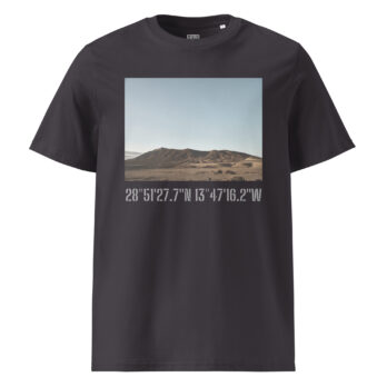 La camiseta unisex Los Ajaches de Volcanica Productions presenta una impresionante imagen de Paisajes Canarios de colinas bajo un cielo azul claro. Un elegante texto blanco debajo de la escena muestra las coordenadas geográficas: 28°5127.7N 13°4716.2W, disponible ahora en nuestra Tienda Online.
