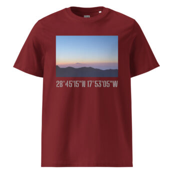 Una camiseta en color granate presenta una imagen rectangular de un paisaje de montaña de La Palma al amanecer o al atardecer, sobre un cielo despejado y degradado. Debajo de la imagen, las coordenadas blancas 28°45′15″N 17°53′05″W resaltan Paisajes Canarios. Este producto, llamado "Camiseta unisex Amanecer desde el Roque de los Muchachos", ya está disponible en nuestra Tienda Online.