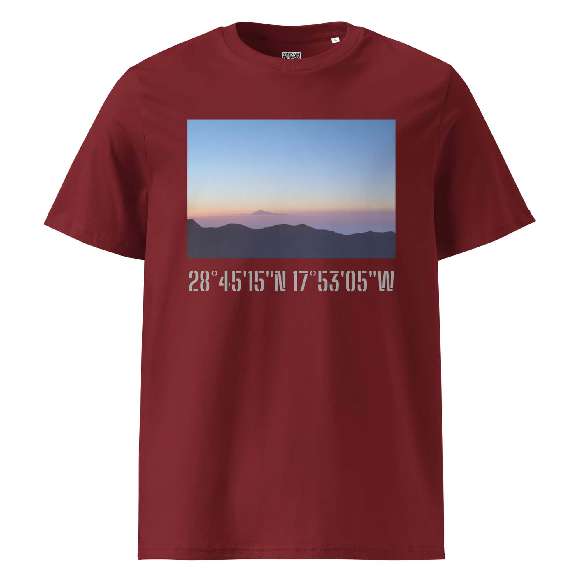 Una camiseta en color granate presenta una imagen rectangular de un paisaje de montaña de La Palma al amanecer o al atardecer, sobre un cielo despejado y degradado. Debajo de la imagen, las coordenadas blancas 28°45′15″N 17°53′05″W resaltan Paisajes Canarios. Este producto, llamado "Camiseta unisex Amanecer desde el Roque de los Muchachos", ya está disponible en nuestra Tienda Online.