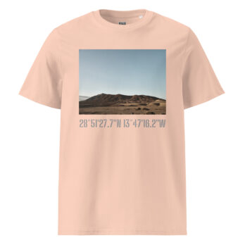 Experimenta la moda moderna con la "Camiseta unisex Los Ajaches" en color beige, que presenta un paisaje desértico de colinas onduladas bajo un cielo azul. Debajo de la obra de arte, encontrarás las coordenadas 28° 51' 27.7"N 13° 47' 16.2"W elegantemente impresas, que encapsulan el espíritu de Paisajes Canarios.