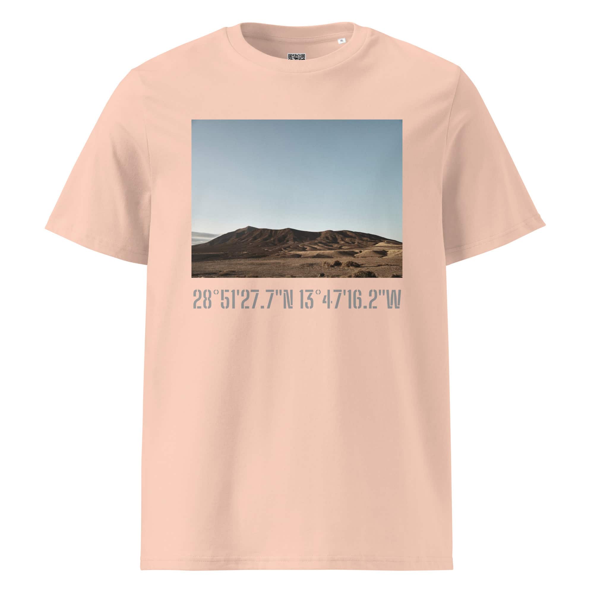 Experimenta la moda moderna con la "Camiseta unisex Los Ajaches" en color beige, que presenta un paisaje desértico de colinas onduladas bajo un cielo azul. Debajo de la obra de arte, encontrarás las coordenadas 28° 51' 27.7"N 13° 47' 16.2"W elegantemente impresas, que encapsulan el espíritu de Paisajes Canarios.