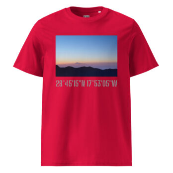 La camiseta unisex Amanecer desde el Roque de los Muchachos, diseñada por Volcanica Productions, presenta una imagen de un paisaje de una montaña distante al atardecer. Muestra tonos azules y naranjas en el cielo sobre colinas oscuras, con el texto "Paisajes Canarios" y las coordenadas 28°45'15"N 17°53'05"W en gris debajo de la imagen.
