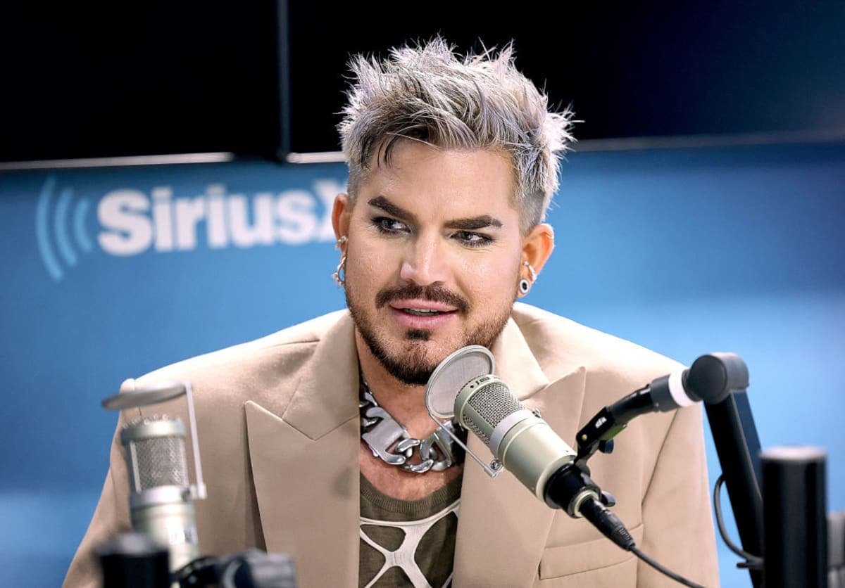 Adam Lambert On Stage, Symbolizing The Success And Opulence Of His Music Career And Financial Ventures.