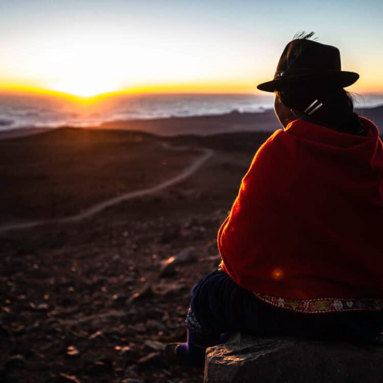 Chimborazo providence at Chimborazo volcano, Ecuador 21/sep/2013 a young indigenous, resting on a rock waiting to the sun to set over the clouds.