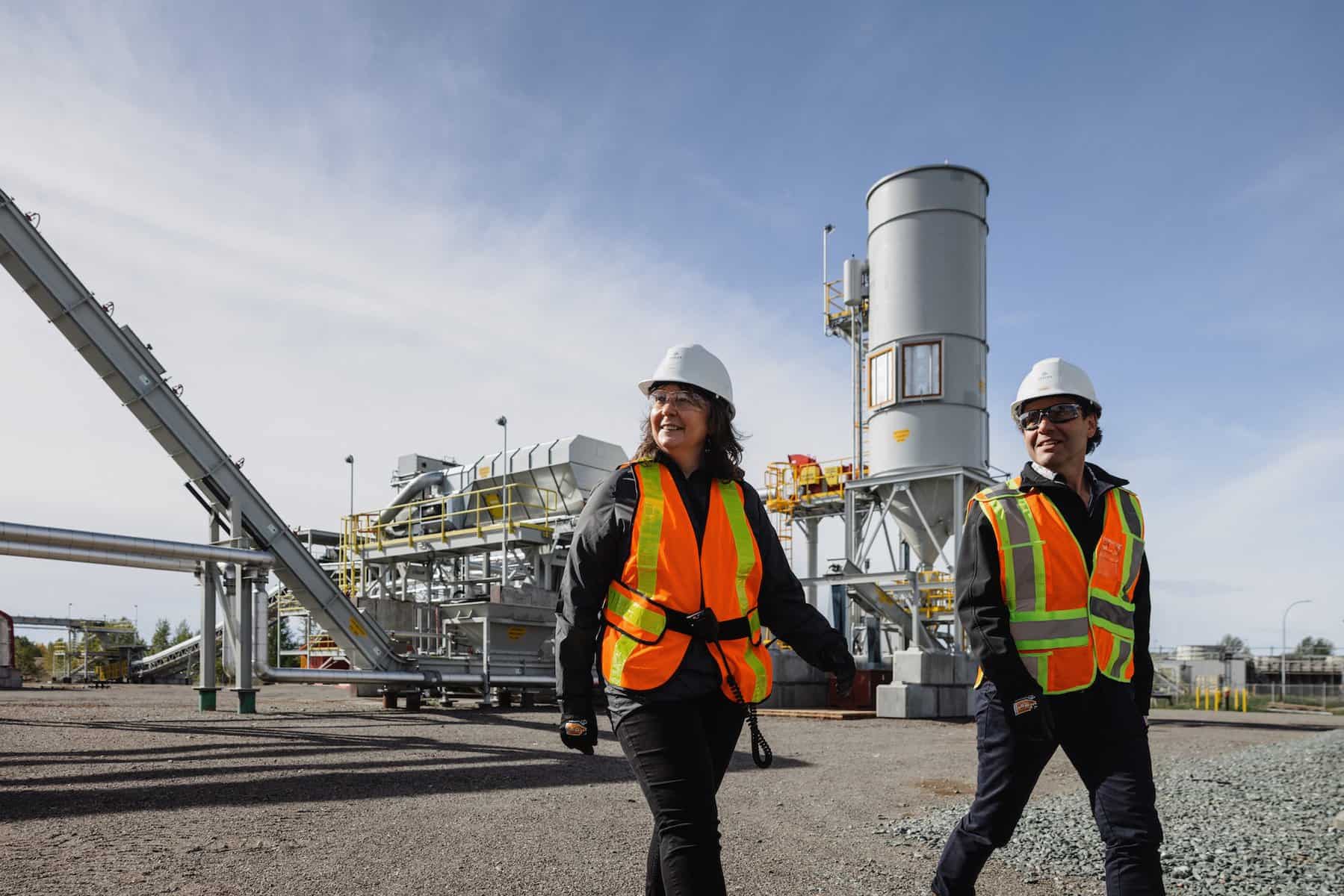 Two people walking through the Arbios Chuntoh Ghuna facility