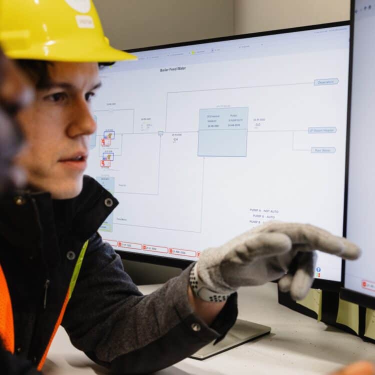 Two people point at the screen in a control room