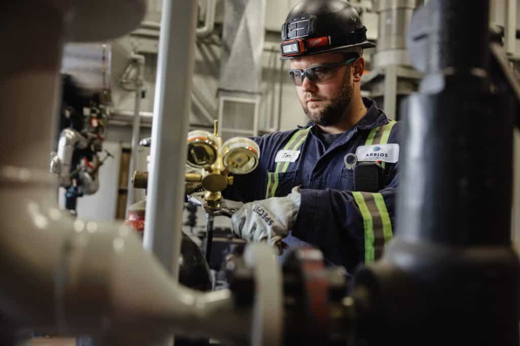 a man wearing hard hat and gloves working on a machine