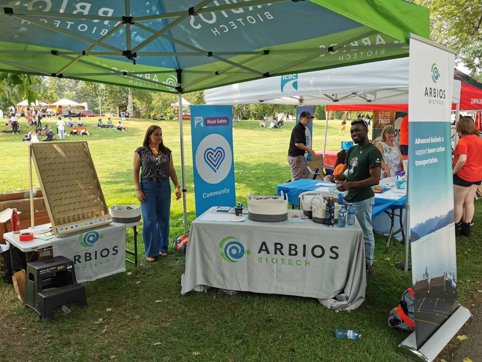 Members of Arbios stand at a booth under a tent