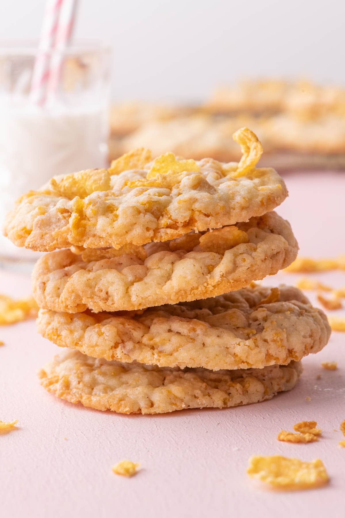 A stack of chewy homemade cornflake cookies with a glass of milk in the background, perfect for an easy nostalgic treat.