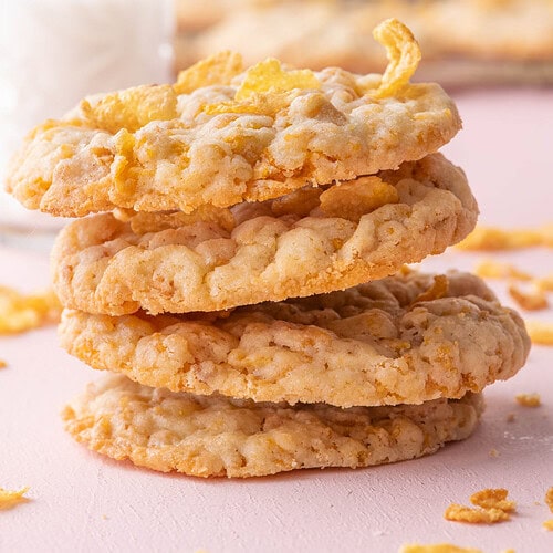 Stack of thin and crispy cornflake cookies with a glass of milk.