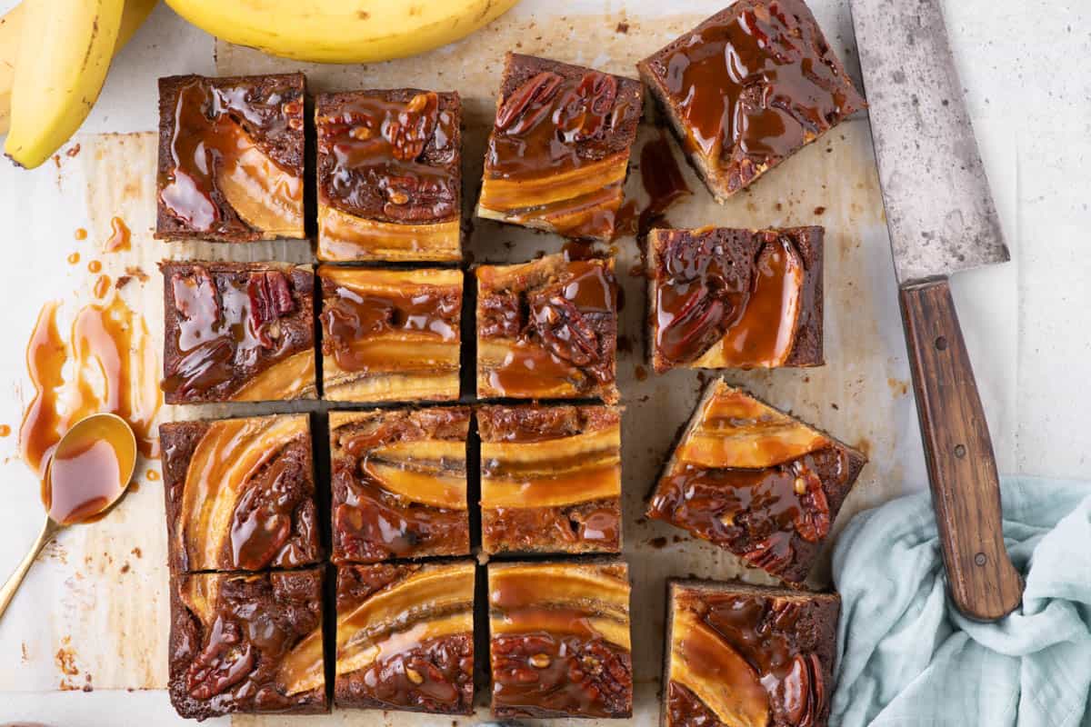 Overhead shot of salted caramel banana bread bars with caramel drips and ripe bananas