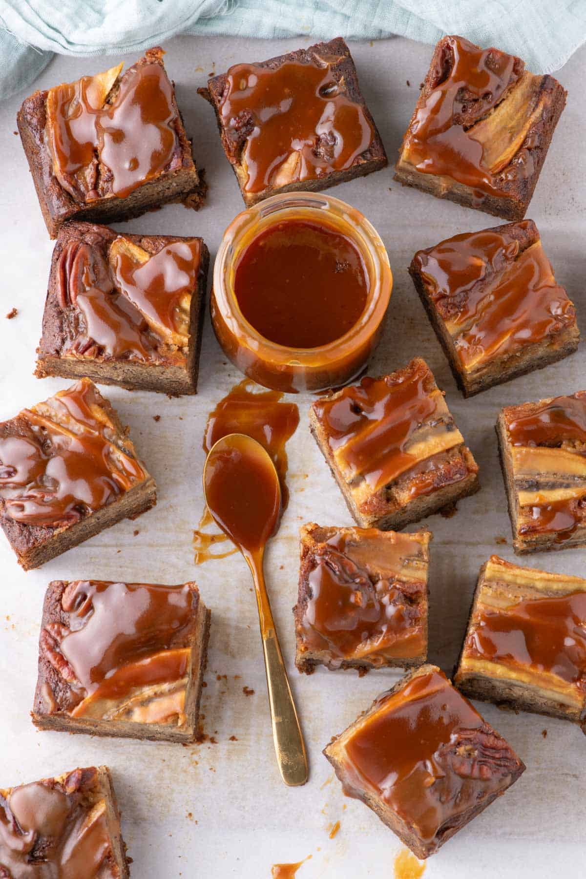 Salted caramel banana bread bars cut into squares with a jar of caramel in the center.