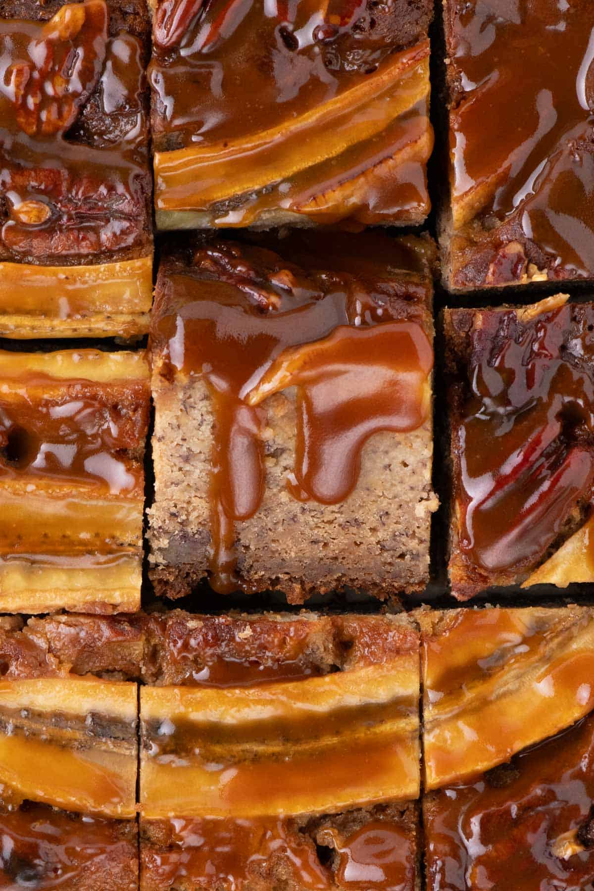 Overhead view of neatly sliced banana bread bars with caramel drizzle and banana decoration.