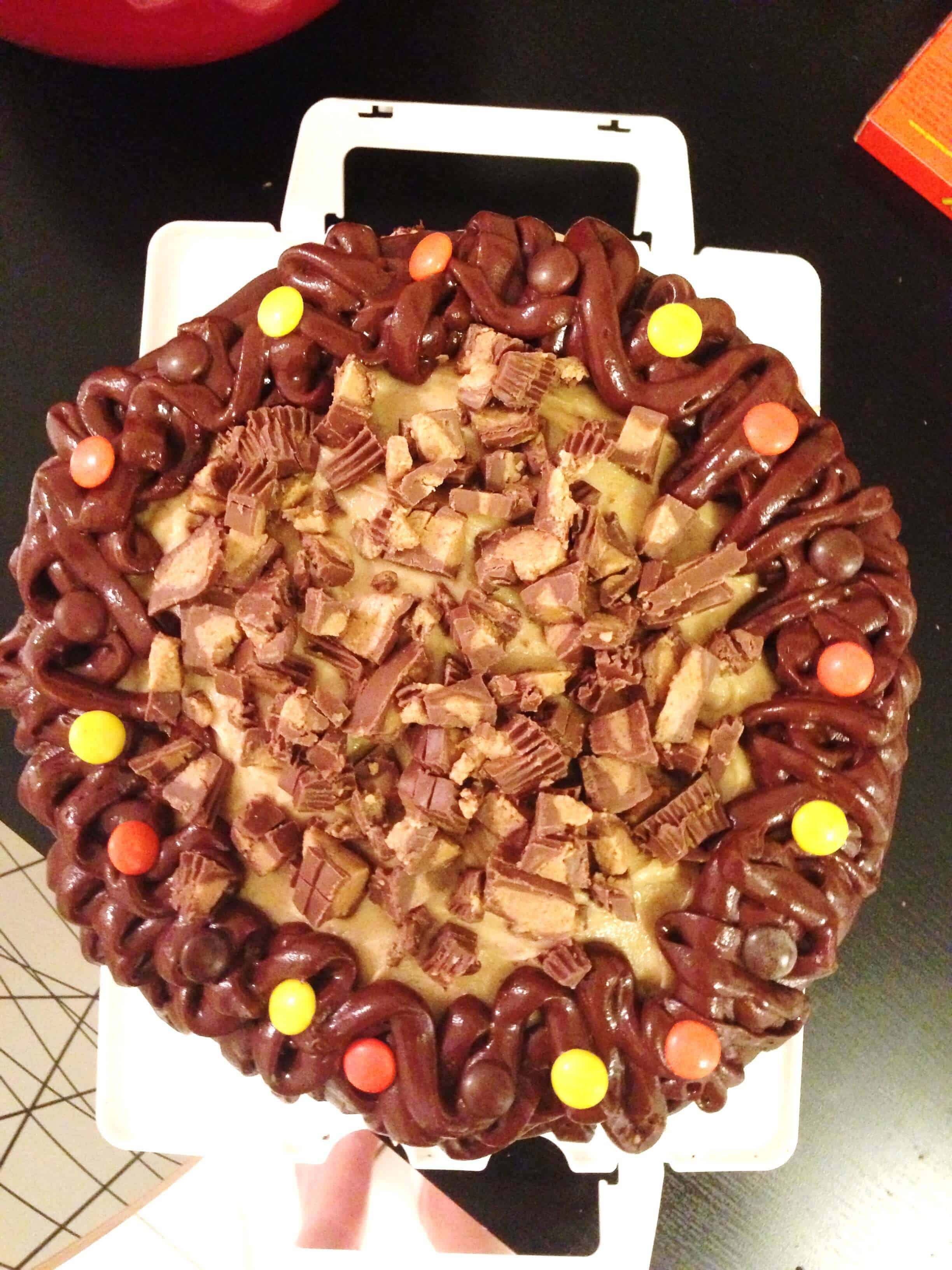 image of a reese's peanut butter cup cake that's topped with peanut butter cups and reese's pieces