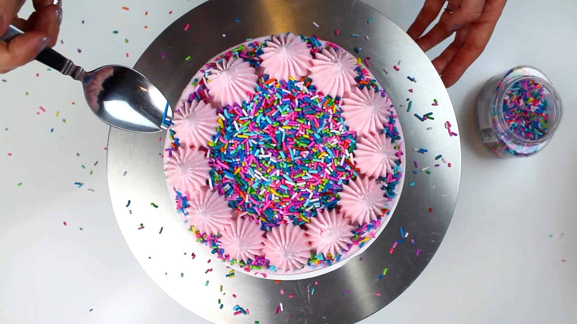 image of vegan almond cake decorate with vegan almond frosting and vegan sprinkles

