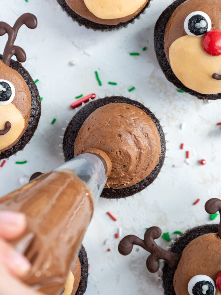 image of chocolate buttercream being piped onto a chocolate cupcake with a large round piping tip