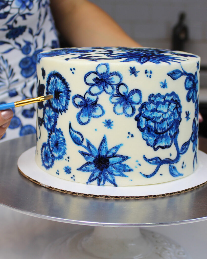image of a painted buttercream cake decorated with hand painted blue flowers using gel food coloring and vodka to make edible paint