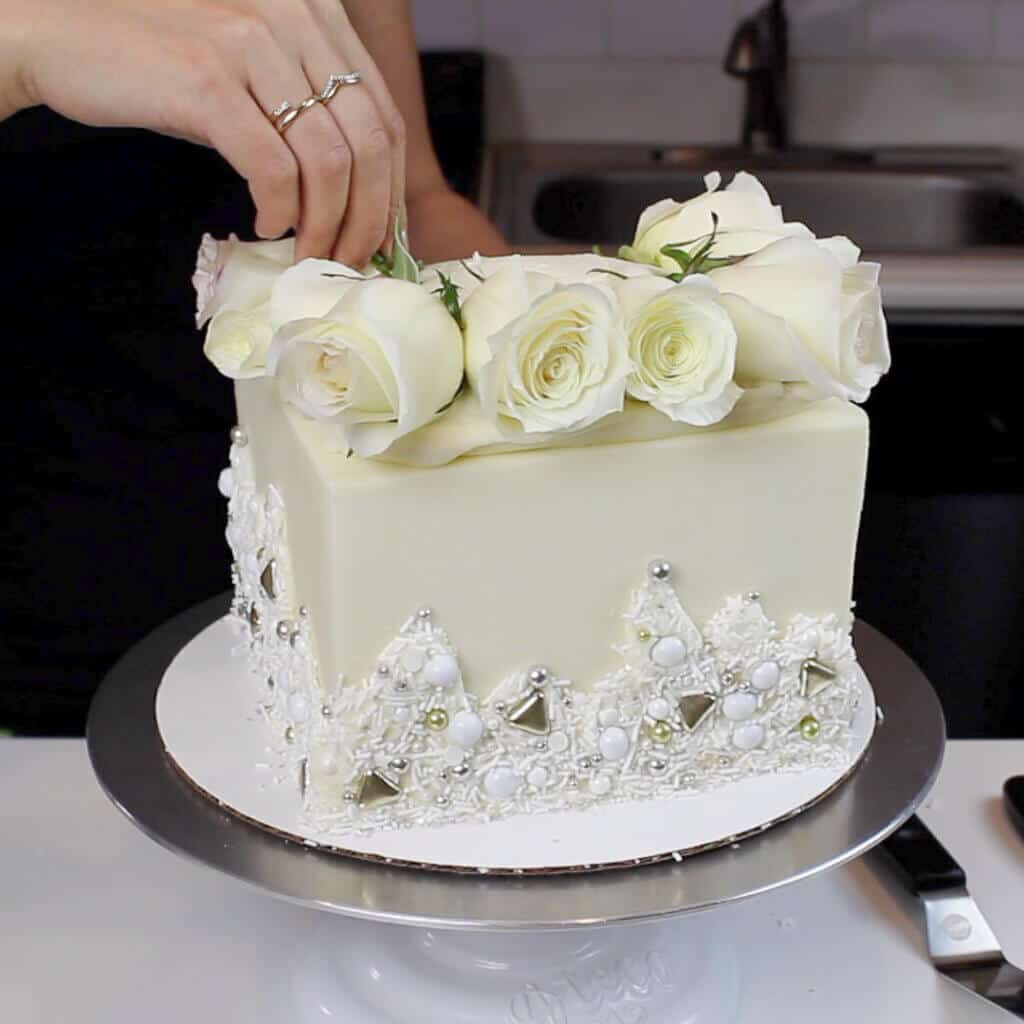 adding fresh white roses to a wedding cake image