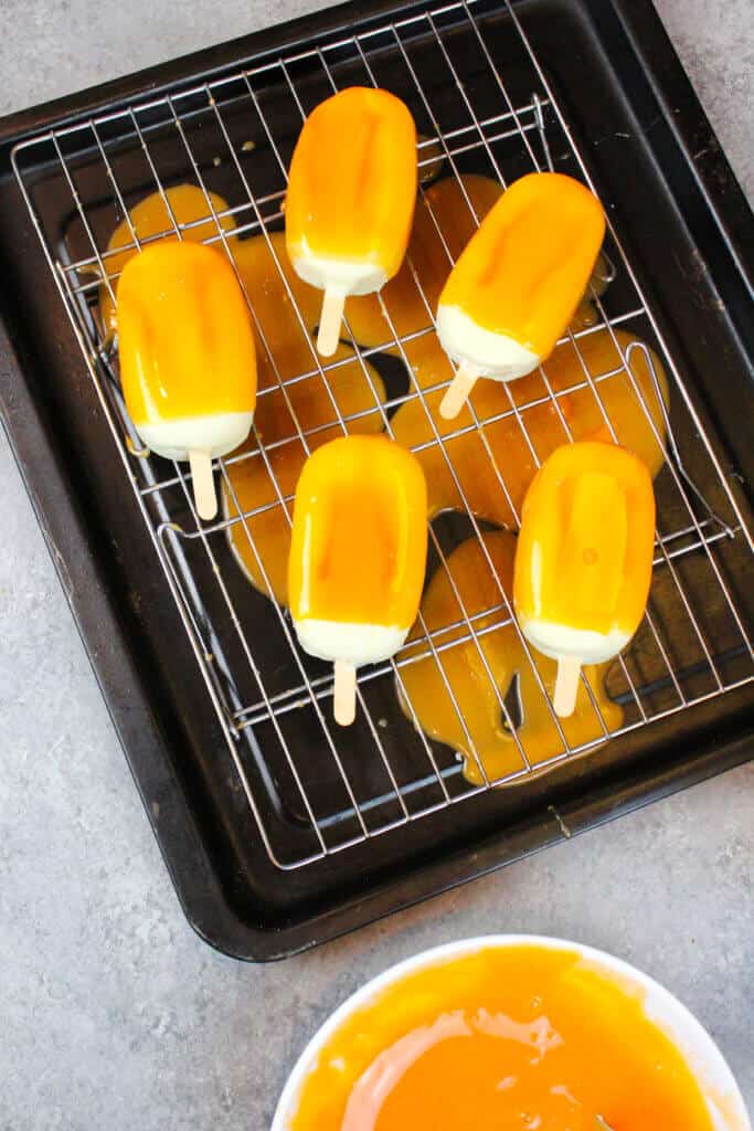 image of orange creamsicle cakesicles, covered in orange mirror glaze