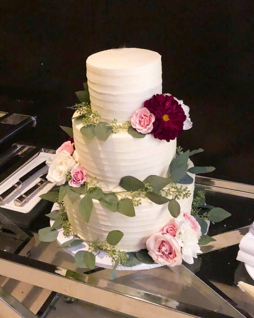 photo of finished wedding cake decorated with fresh flowers and greenery