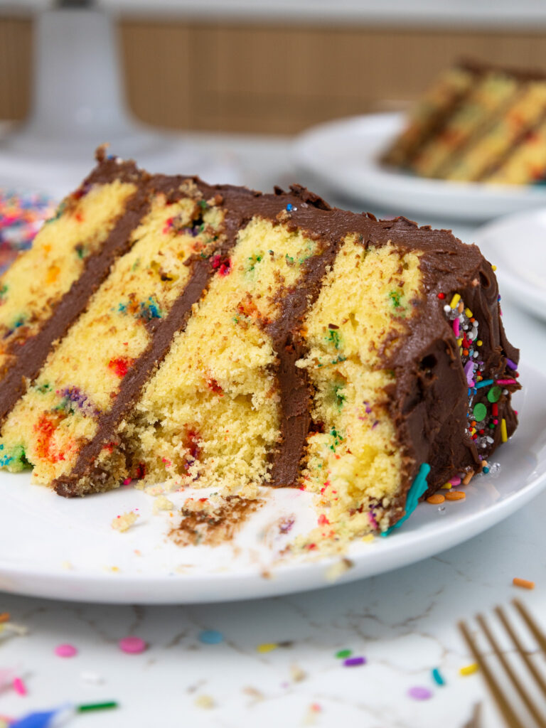 image of a slice of yellow cake that's been cut into to show it's tender crumb and chocolate buttercream