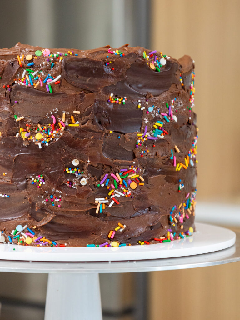 image of a yellow layer cake that's been frosted with chocolate buttercream and decorated with cute sprinkles