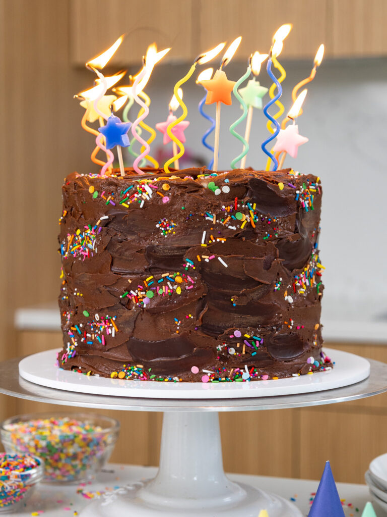 image of a cute yellow birthday cake that's been frosted with chocolate buttercream and decorated with fun candles
