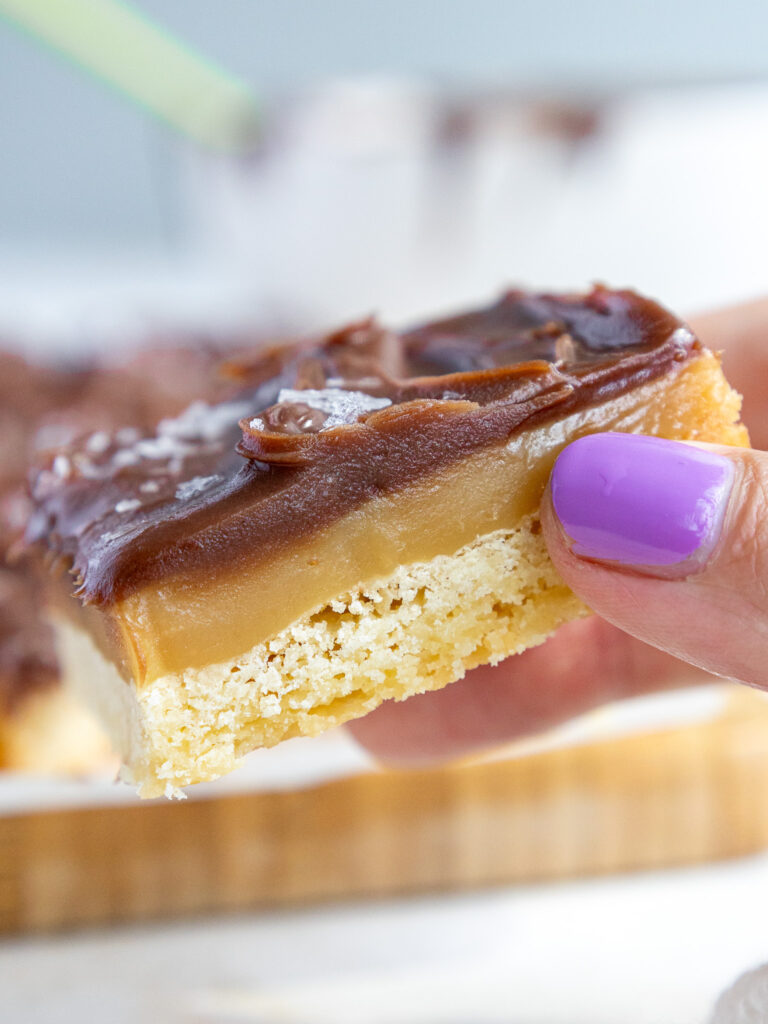 image of a millionaire bar that's been cut into a square to show it's thick layers of shortbread, caramel, and chocolate ganache