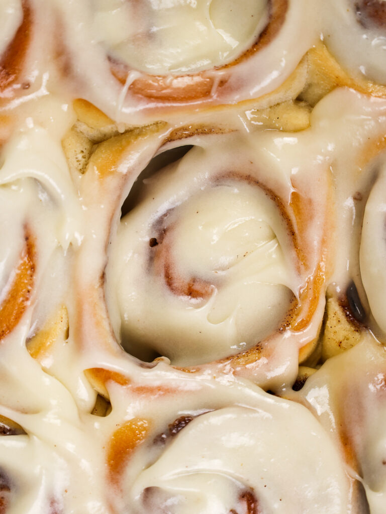 image of frosted quick yeast cinnamon rolls that have been slathered with cream cheese frosting