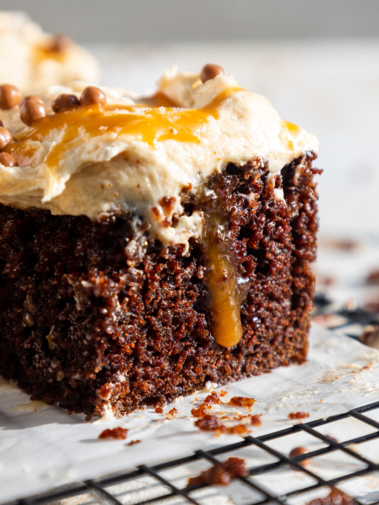 image of a slice of chocolate caramel poke cake that's been cut into to show a pocket of caramel
