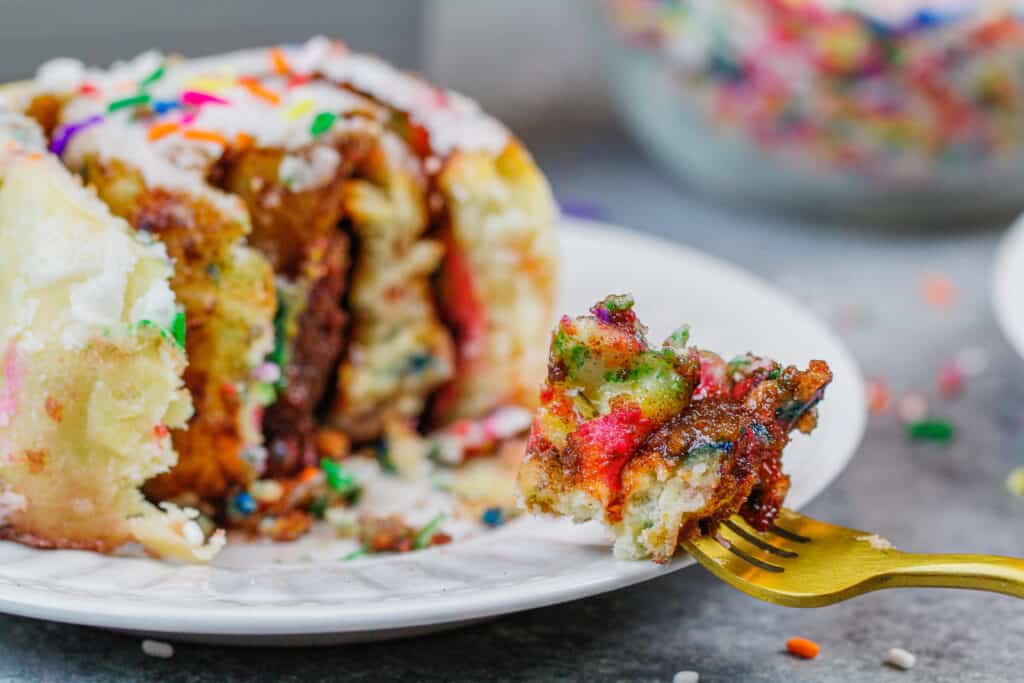 image of a bite of a sprinkle cinnamon roll on a fork, ready to be eaten
 