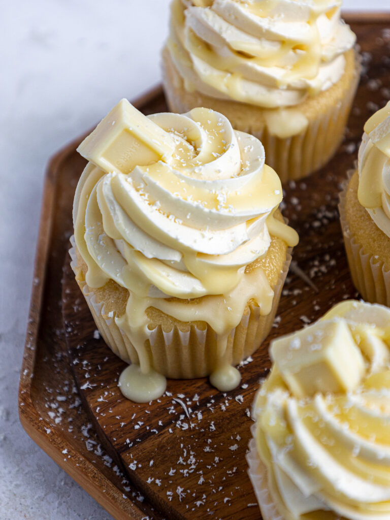 image of white chocolate cupcakes that have been decorated with white chocolate buttercream and drizzled with white chocolate ganache