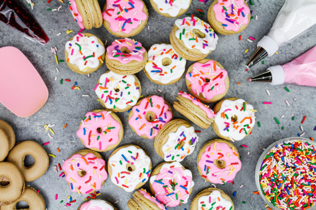 image of donut macarons decorated with royal icing to look just like little frosted sprinkle donuts