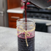 image of blueberry simply syrup being poured into a mason jar for storage