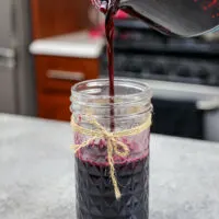 image of blueberry simply syrup being poured into a mason jar for storage