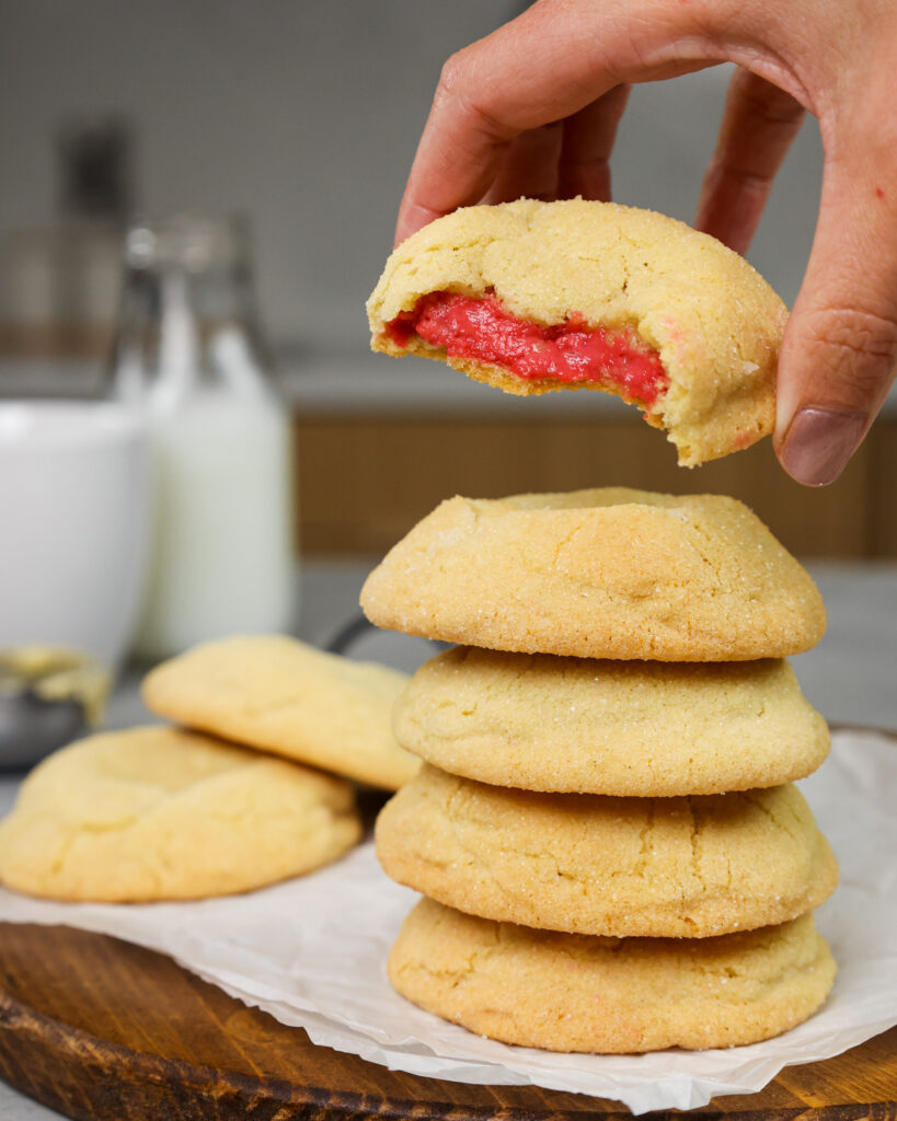image of raspberry cheesecake cookies that have been bit into to show their raspberry cheesecake filling