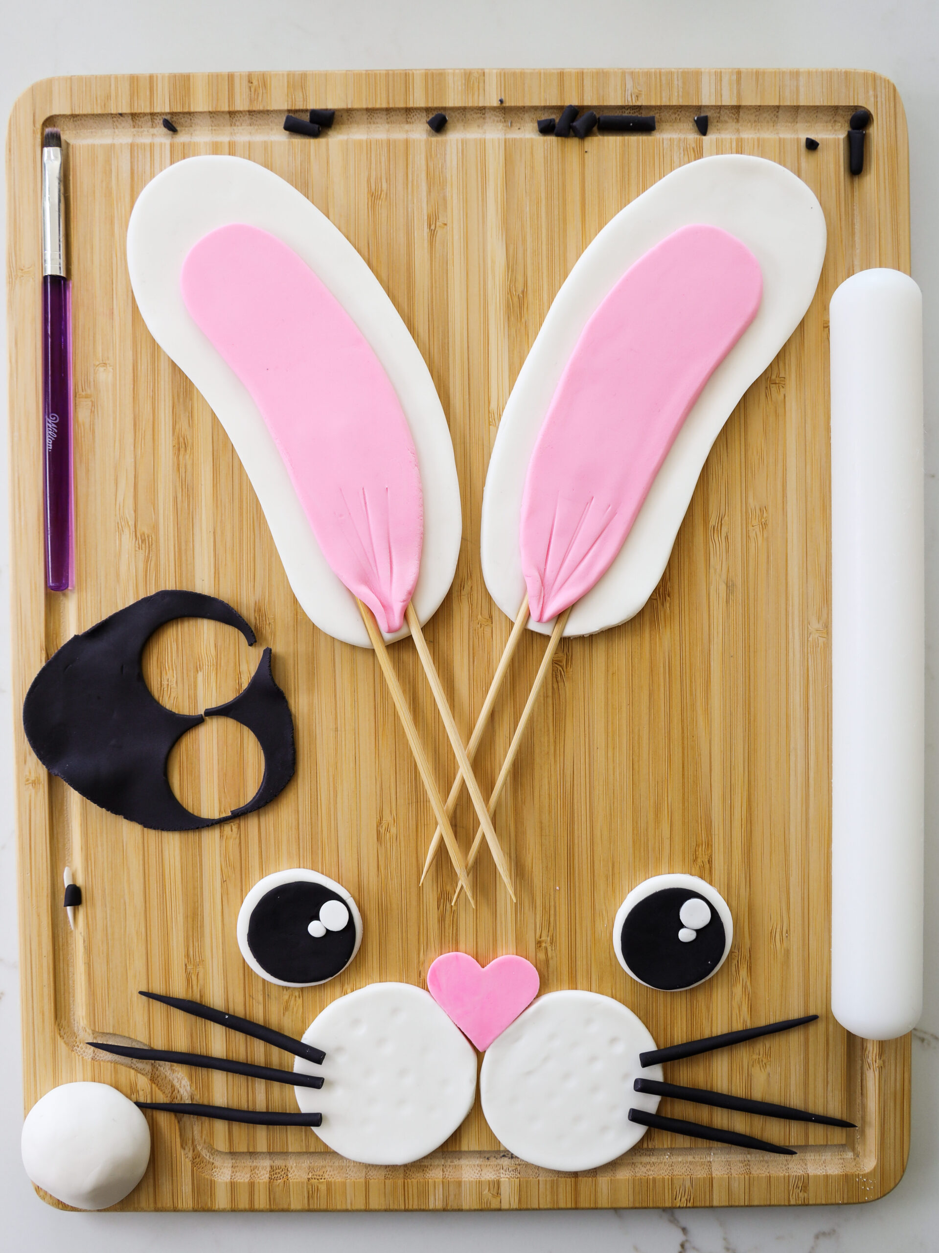 image of a bunny rabbit face and ears that've been made with fondant to decorate a rabbit cake 