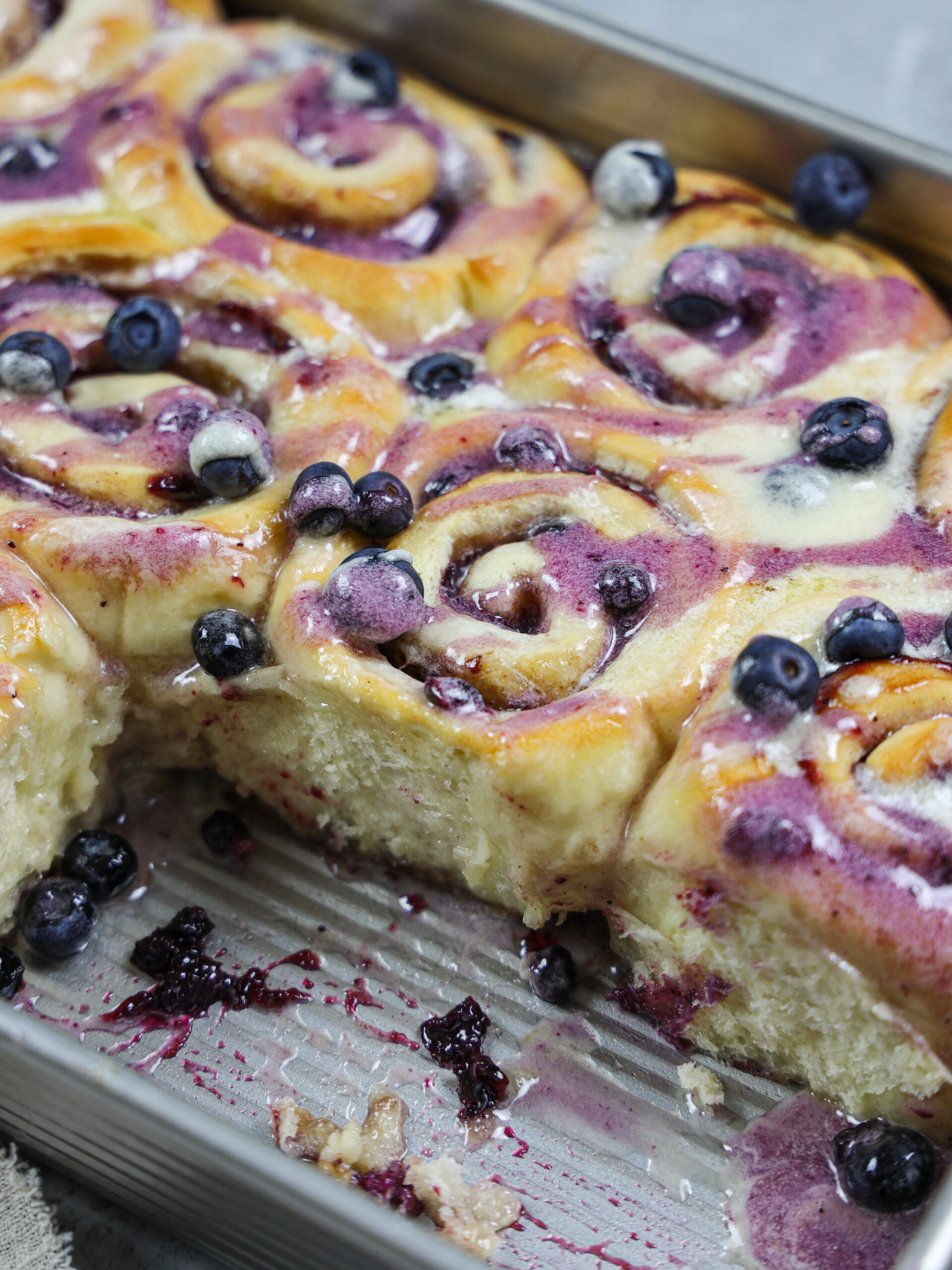 image of blueberry cinnamon rolls that have been baked and drizzled with vanilla and blueberry glaze