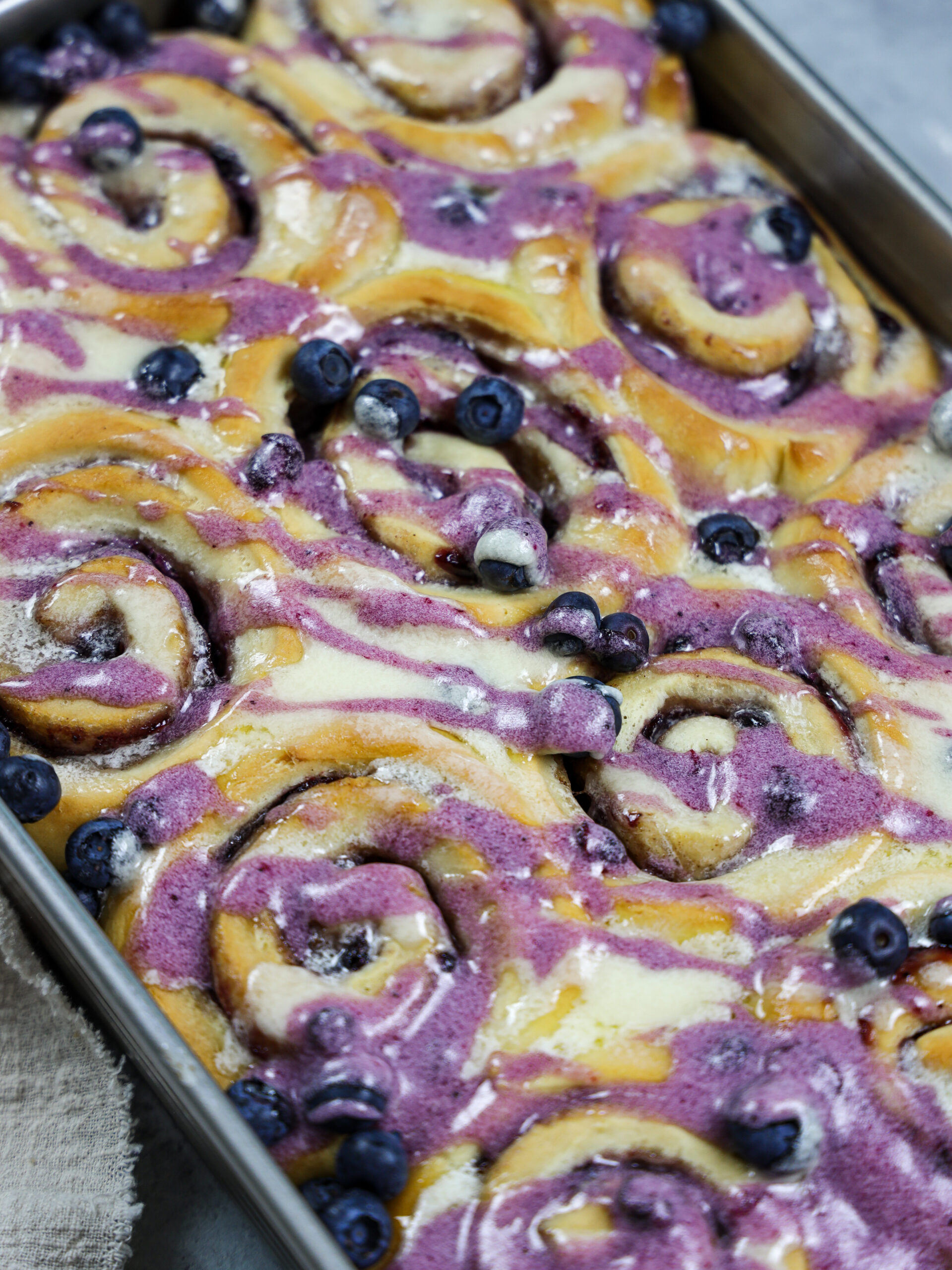 image of blueberry cinnamon rolls that have been baked and drizzled with vanilla and blueberry glaze