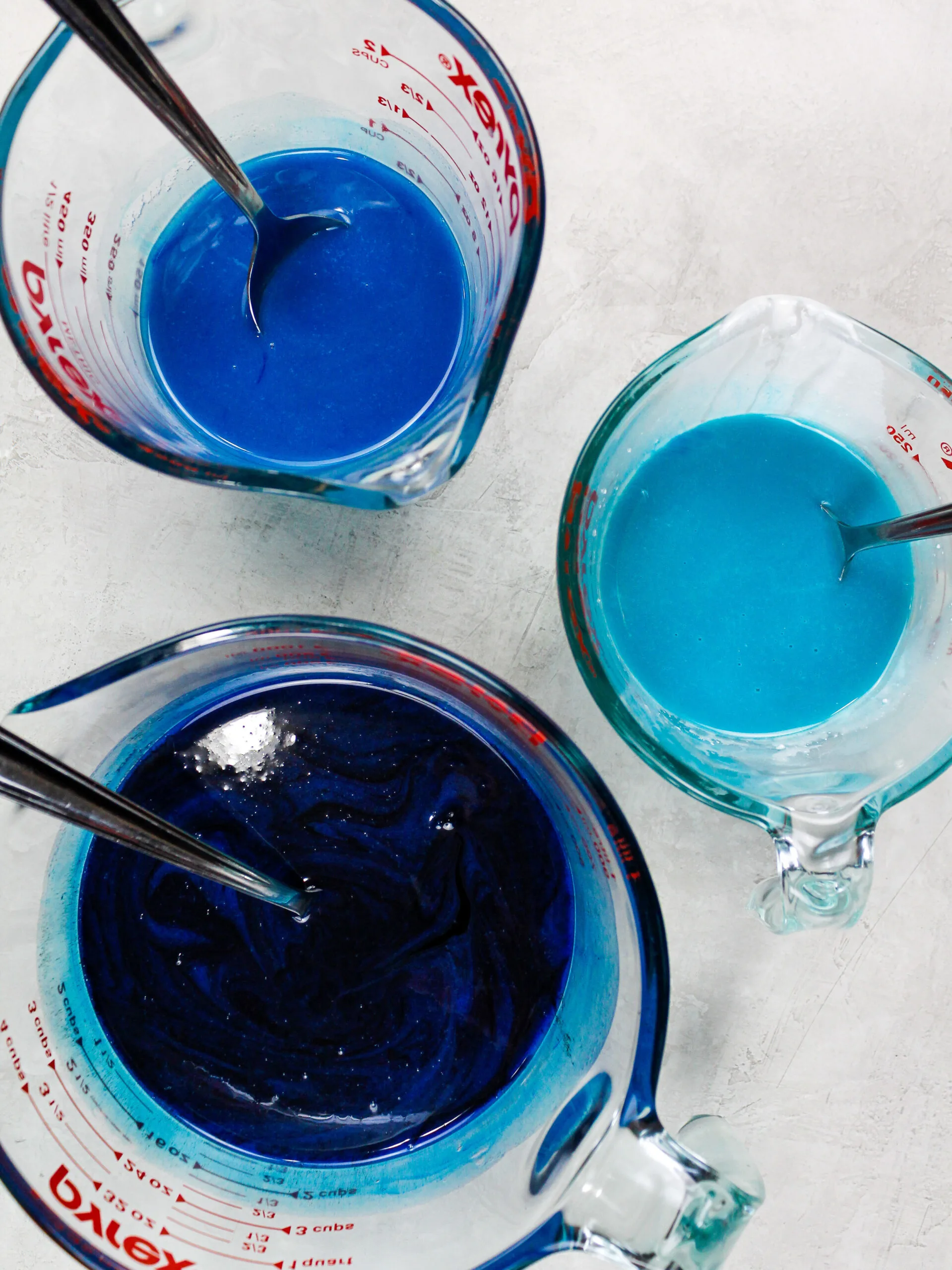 image of three shades of blue mirror glaze ready to be used to make an ocean themed cake