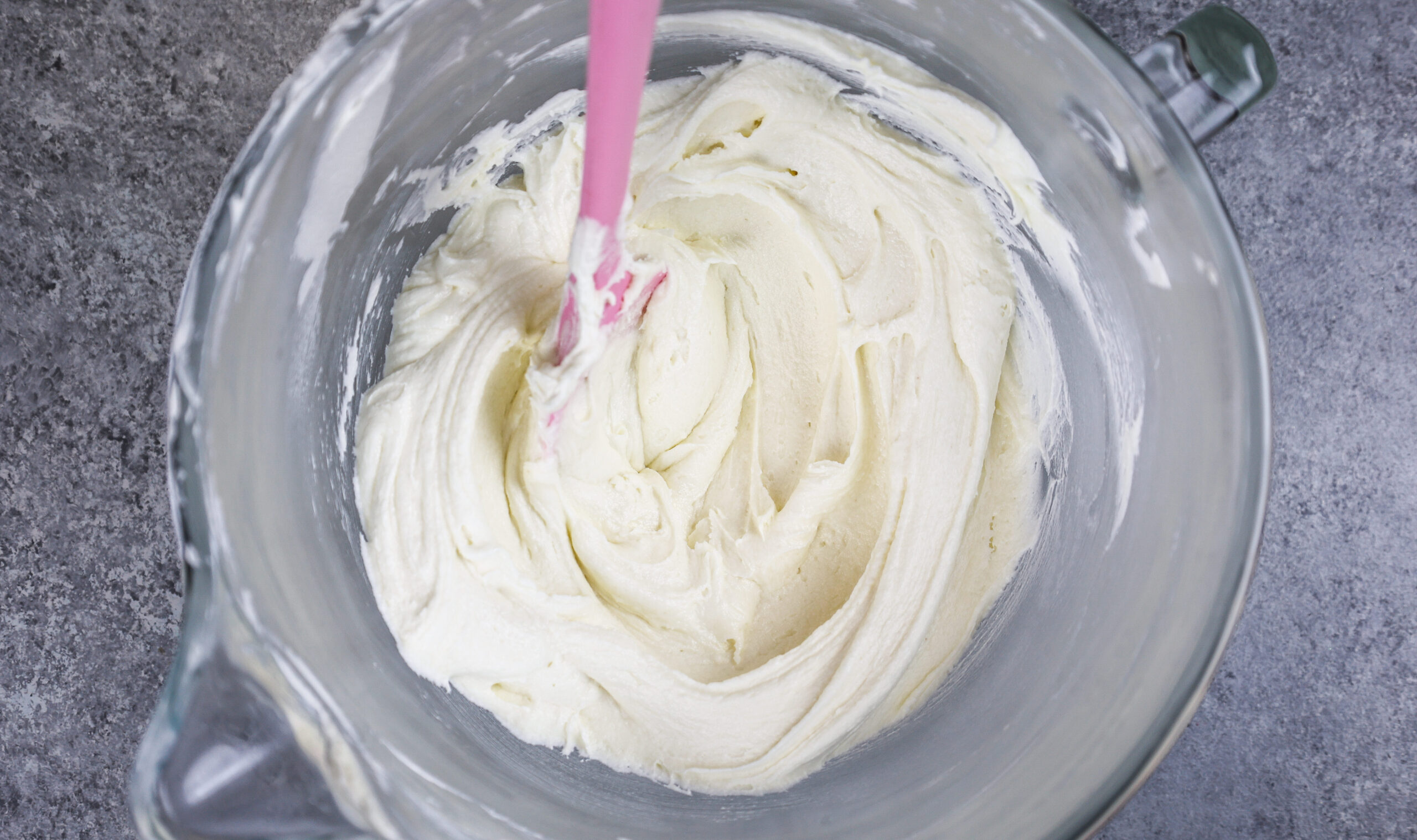 image of vanilla american buttercream in bowl that's been stirred with a spatula to make it super smooth