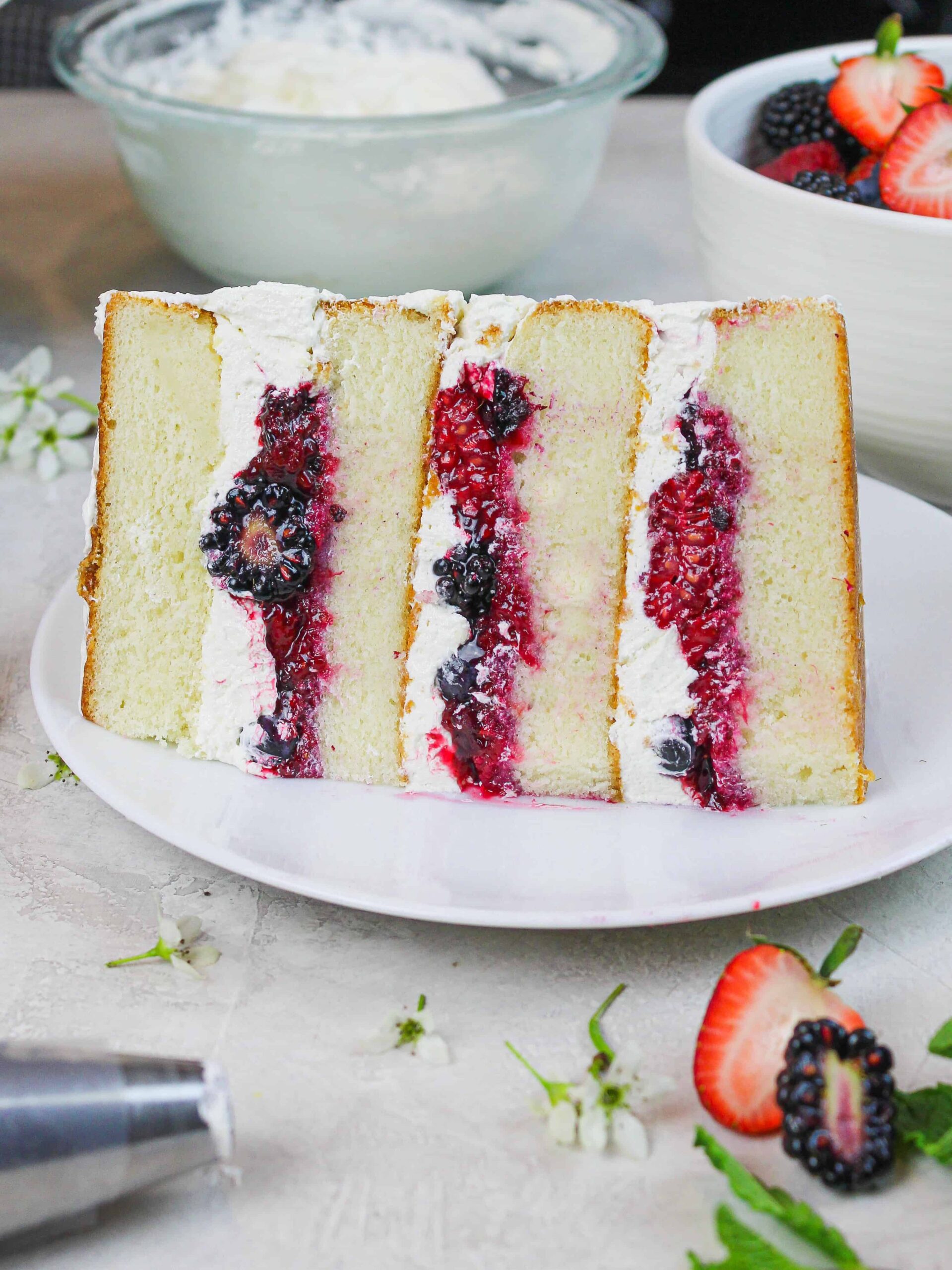 photo of a slice of berry chantilly cake showing mixed berry filling and fluffy mascarpone cream and soaked with blueberry simple syrup