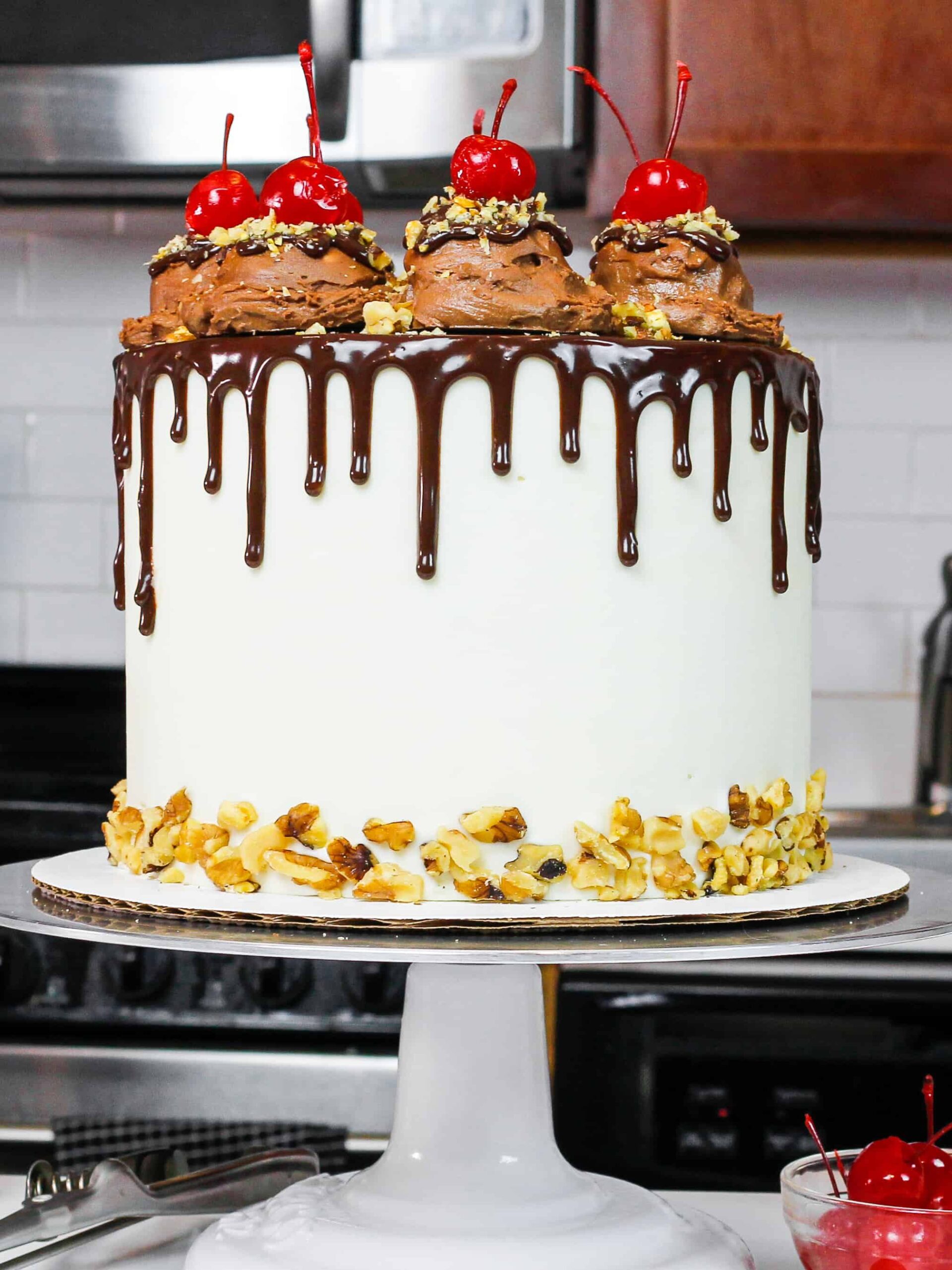 image of a rocky road cake made with fluffy chocolate cake layers, marshmallow frosting, and decorate with ice cream scoops and a chocolate drip