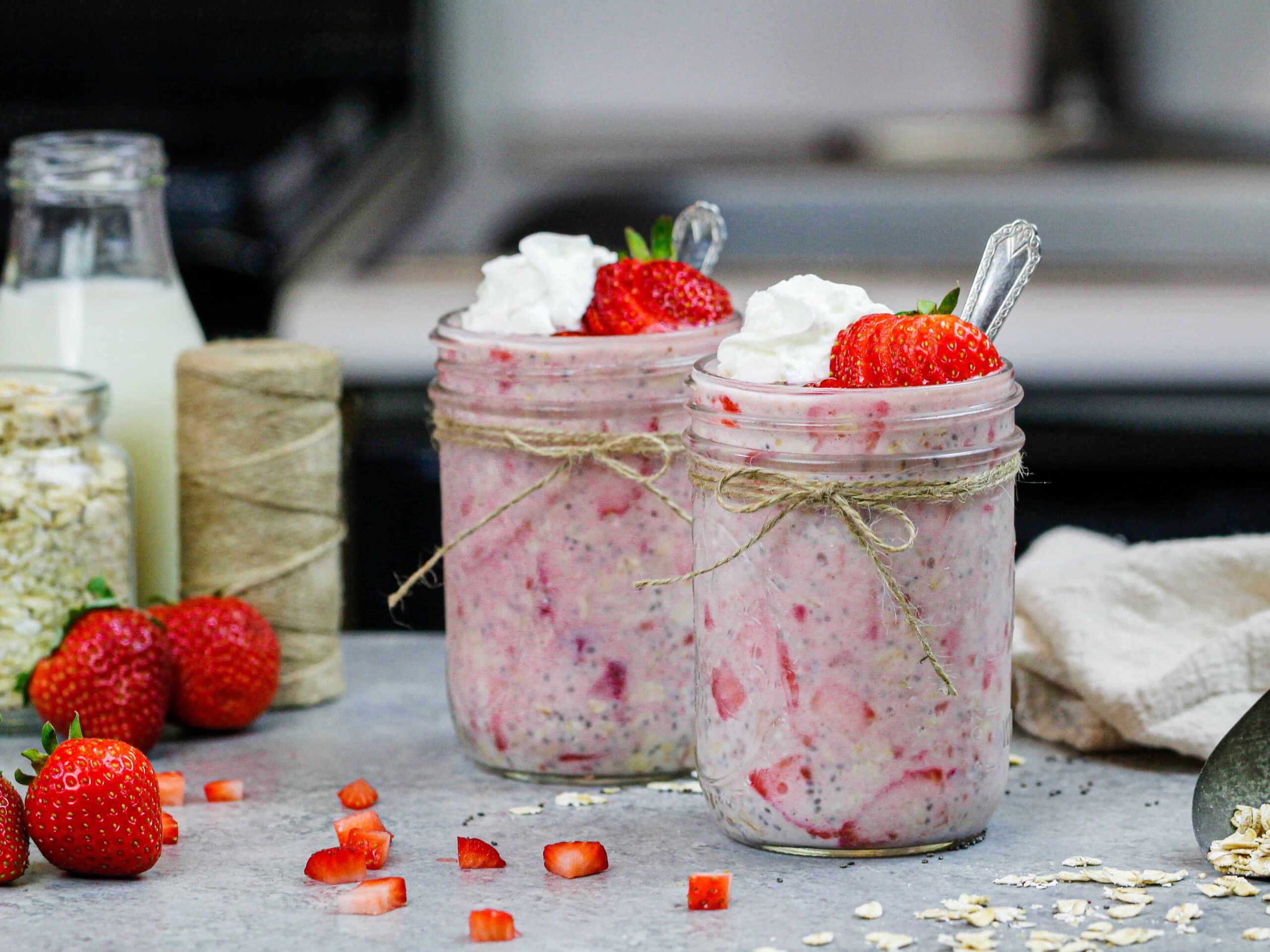 image of strawberry overnight oats made in cute mason jars and topped with a dollop of whipped cream and sliced strawberries